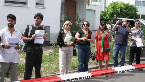 Mehrere Menschen halten Schilder und die afghanische Nationalflagge hoch 