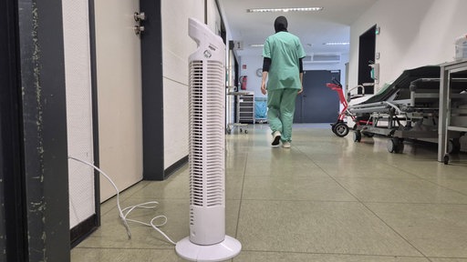 Ein kleiner weißeer Ventilator steht im Flur eines Krankenhauses.