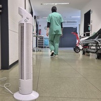 Ein kleiner weißeer Ventilator steht im Flur eines Krankenhauses.