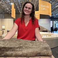 Lotta Westdorf schaut in die Kamera. Vor ihr ein Stein