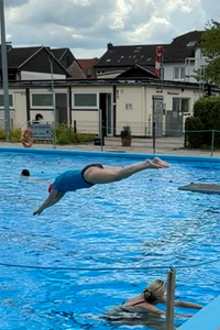 Eine Besucherin des Freibads in Bonn Friesdorf springt ins Wasser. 
