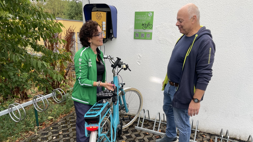 Vereinsmitglieder zeigen die Ladestation für E-Bikes am Vereinshaus
