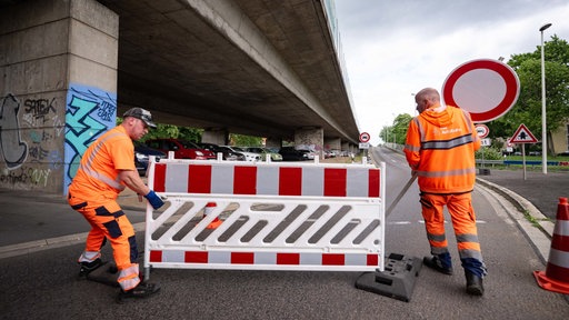 2 Arbeiter stellen eine Absperrung vor eine Autobahnauffahrt