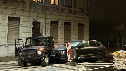 Zwei Autos, darunter ein geklauter Geländewagen, stehen nachts beschädigt auf einer Straße.