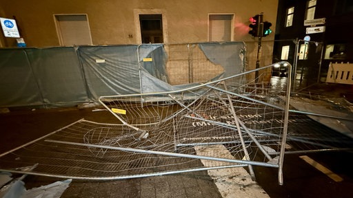 Ein demolierter und umgestürzter Baunzaun liegt nachts in Bonn auf der Straße.