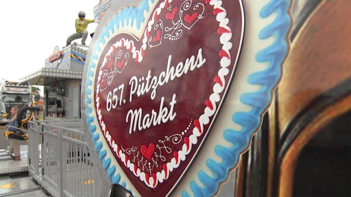 Ein Schild in Form eines Lebkuchenherzes mit der Beschriftung "657. Pützchens Markt"