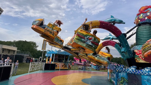 Buntes Fahrgeschäft das aussieht wie eine Krake bei Rhein in Flammen. Mehrere Menschen sitzen mit wehenden Haaren darin. 