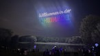 Drohnen formen die Worte "Wilkommen in der Rheinaue" über dem Himmel in der Rheinaue