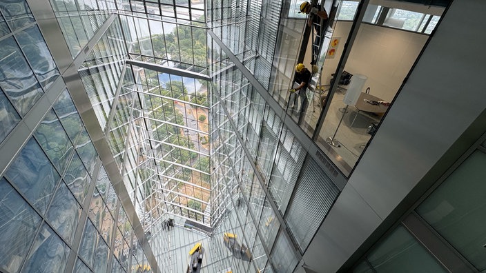 Zwei Techniker lösen die Stahlseile der Gondel im Post Tower in Bonn.