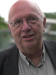 Mann im Anzug, mit Brille schaut in die Kamera. 