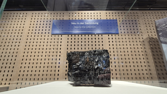 Ein Stück Steinkohle steht auf einem Podest in einer Vitrine.