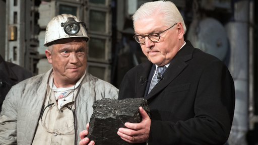 Bundespräsident Frank-Walter Steinmeier hält das letzte Stück Steinkohle, das in Deutschland gefördert wurde in den Händen.