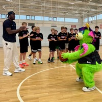 Jugendliche, ein großer Mann und ein Maskottchen spielen Basketball