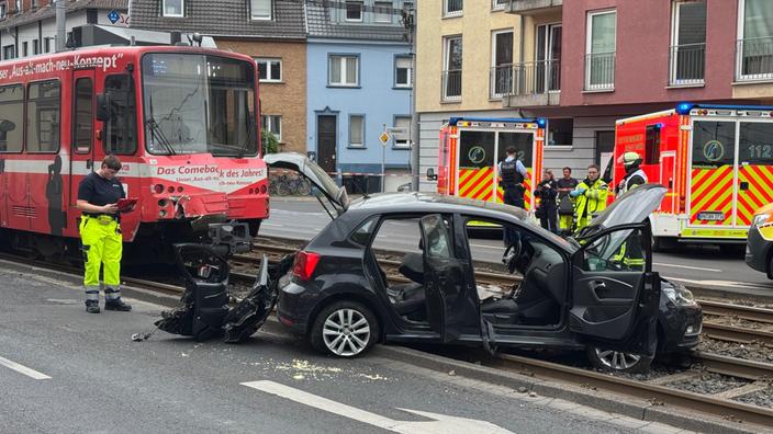 Nach dem Unfall ist der Pkw stark beschädigt und Einzelteile liegen auf der Fahrbahn und den Schienen.