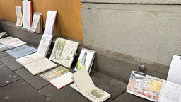 Das Bild zeigt Notizbücher in einer Reihe mit Zeichnungen