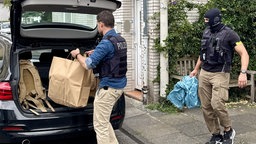 Polizeibeamte packen Papiertüten in einen Kofferraum
