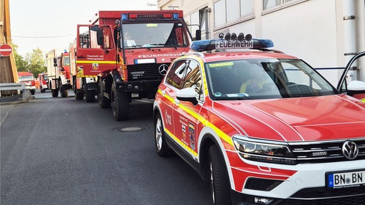 Rot lackierte Einsatzfahrzeuge der Feuerwehr Bonn stehen in einer Ausfahrt hintereinander