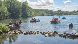 Vier Boote fahren auf dem Neffelsee, eine Person ist im Wasser. 