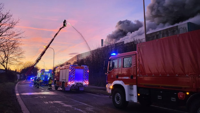 Einsatzkräfte der Feuerwehr löschen einen Brand an einem Recyclingunternehmen im Krefelder Hafen