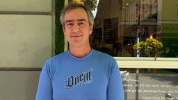 Kiosk-Geschäftsführer Pablo Dege schaut direkt in die Kamera. Er hat ein blaues Oberteil an.