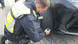 Ein Polizist misst das Reifenprofil eines Autos