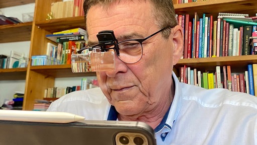 Dieter Holthaus sitzt mit einer speziellen Brille vor dem Laptop