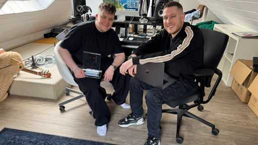 Zwei Männer sitzen vor Rechner an dem sie Musik komponieren.