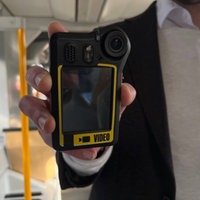 Ein Mann hält eine Bodycam in der Hand.