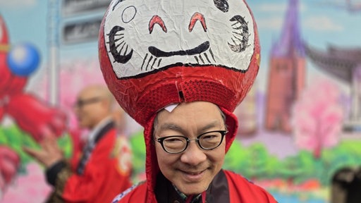 Einer der Macher des ersten japanischen Karnevalswagens trägt eine japanische Karnevalskopfbedeckung.