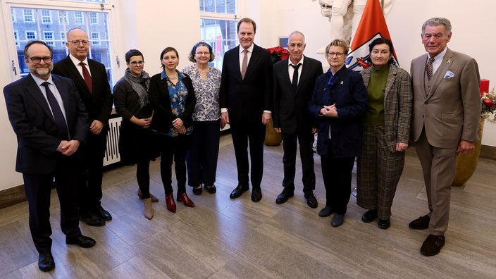 Mehrere Menschen in einer Reihe nebeneinander in einem Saal