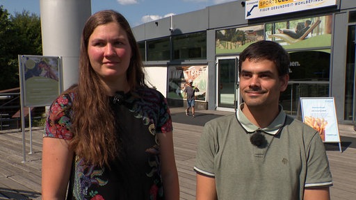 Eine Frau und ein Mann stehen vor dem Eingang des AGGUA in Troisdorf.