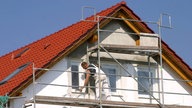 Einfamilienhaus mit Gerüst und Bauarbeiter