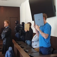 Zwei Männer stehend halten Mappen vor ihr Gesicht