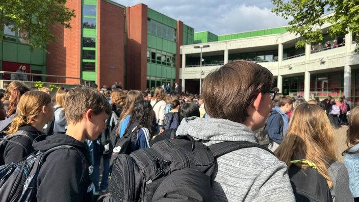Eine Menge von Schülern steht vor dem Schloß-Gymnasium in Benrath und werden begrüßt.