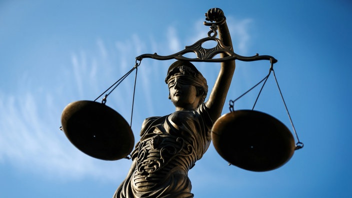 Eine Statue der Justitia hält als Symbol eine Waage in ihrer Hand.