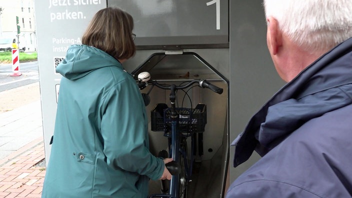 Eine Frau versucht, ihr Rad ins Bonner Fahrrad-Parkhaus zu stellen.