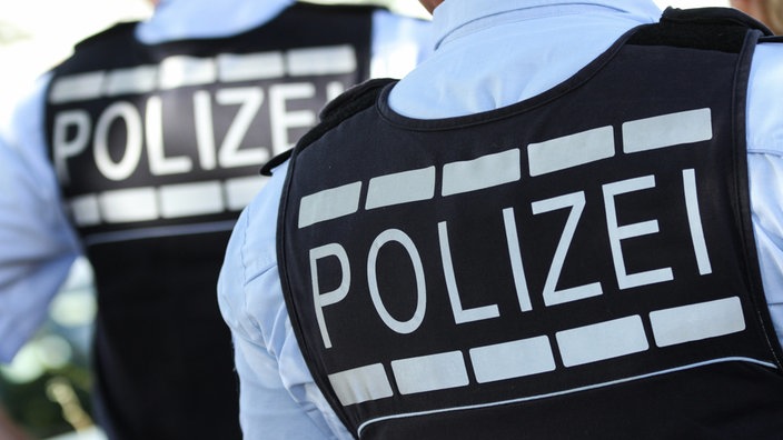 Ein Polizist von hinten mit einem Polizei-Schriftzug auf dem Rücken