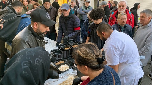 Speisen, wie Hähnchen, Reis oder Linsensuppe werden verteilt. 