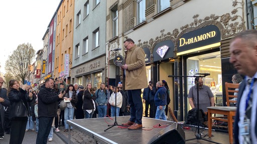 Kölns Oberbürgermeister Torsten Burmester steht auf einer Bühne auf der Keupstraße. 