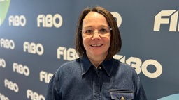 Silke Frank, Chefin der Fibo, vor einer dunkelblauen FIBO-Messewand