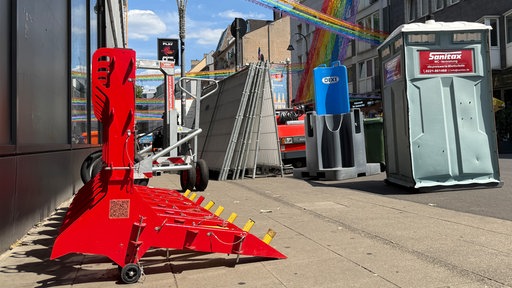 Eine Sicherheitsabsperrung steht in der Schaafenstraße. Dahinter erkennt man bunte Girlanden.