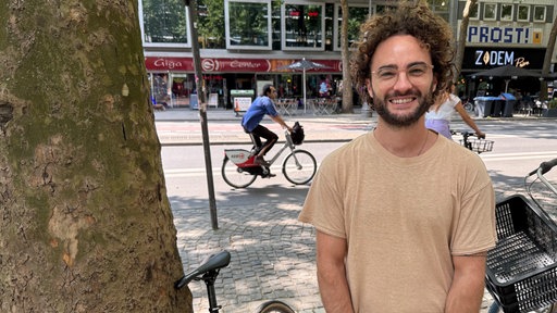 Malte steht neben seinem Fahrrad und einem Baum.