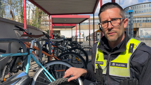 Michael Lorenz hockt neben einem kaputten Kinderfahrrad.