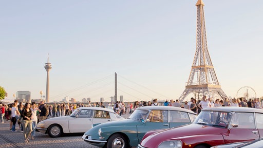 Citroens parken auf dem Burgplatz in Düsseldorf; im Hintergrund der Eiffelturm und der Fernsehturm
