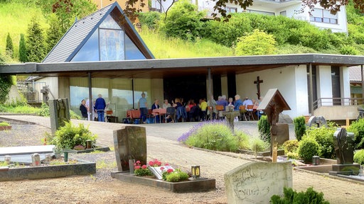 Direkt neben einem Friedhof wird unter einem Vordach Kaffee und Kuchen serviert