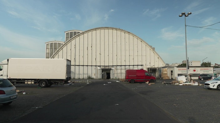 Vorderseite einer weißen Halle und Fahrzeuge auf Parkplatz