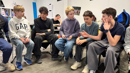 Schüler sitzen im Halbkreis