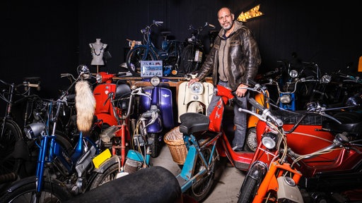 Holger Rick steht zwischen seinen alten Mopeds