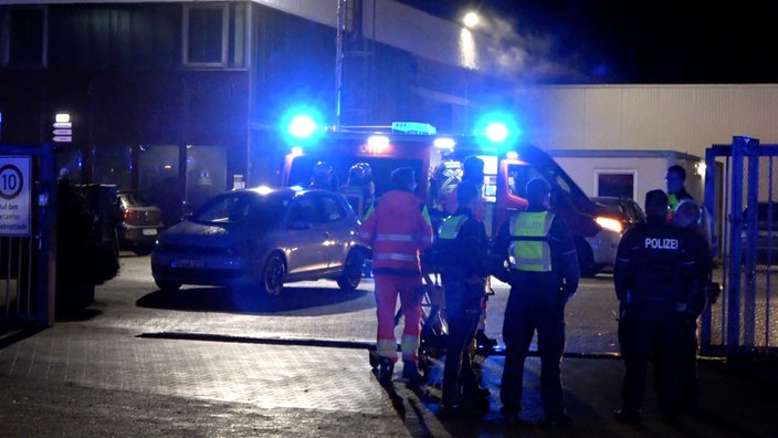Zu sehen sind mehrere Einsatzkräfte der Polizei und Fuerwehr vor der Wäscherei in Ibbenbüren.