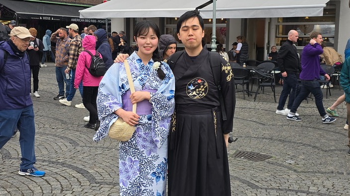 Zwei Menschen in japanisch anmutenden Kleidern vor einem Zelt